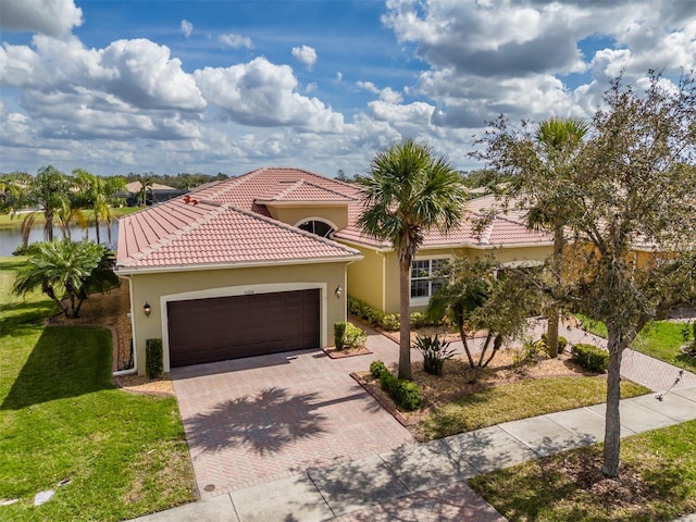 mediterranean / spanish home with a tiled roof, an attached garage, decorative driveway, a front lawn, and stucco siding