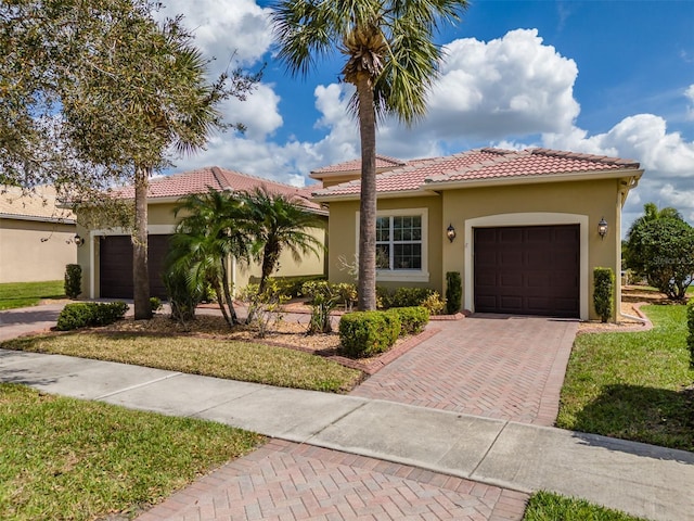 view of front facade with decorative driveway, a tile roof, an attached garage, and stucco siding