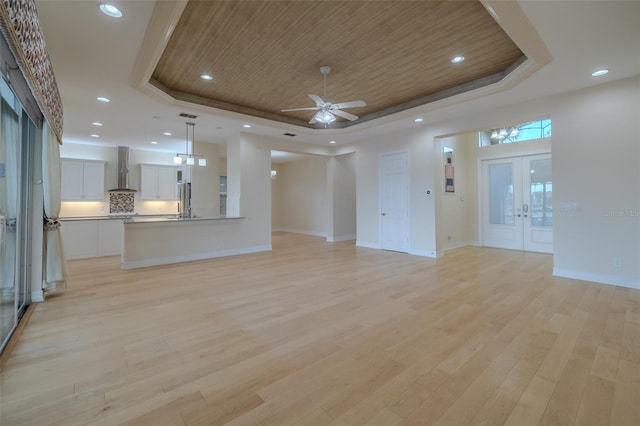 unfurnished living room featuring a raised ceiling, wooden ceiling, french doors, light wood-type flooring, and recessed lighting