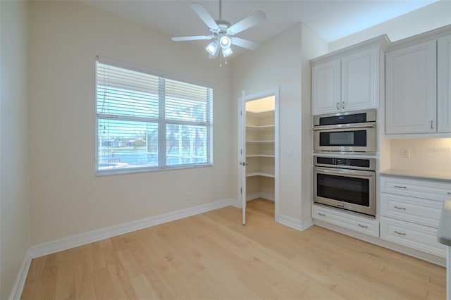 kitchen with light wood-style flooring, white cabinetry, ceiling fan, and stainless steel double oven