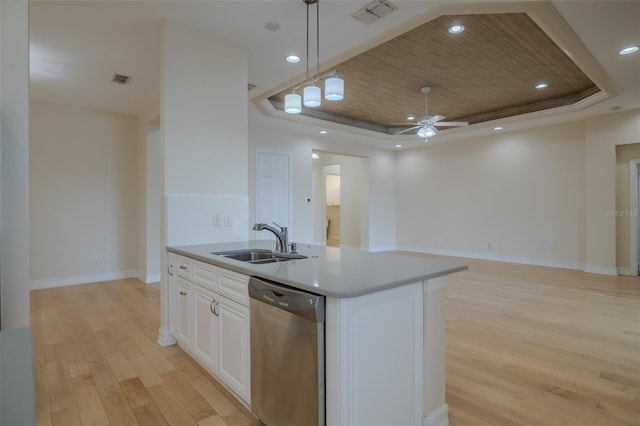 kitchen featuring dishwasher, a tray ceiling, a sink, and visible vents