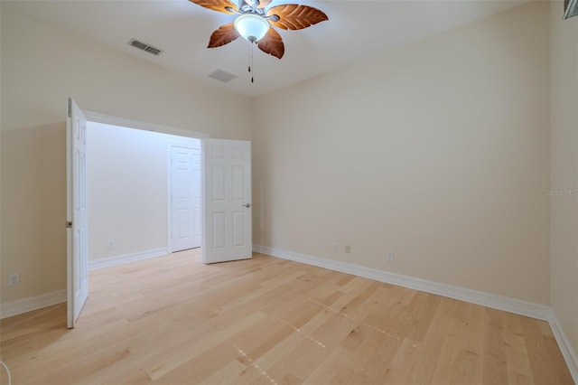 spare room featuring a ceiling fan, light wood-type flooring, visible vents, and baseboards