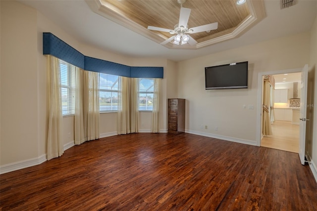 empty room with wood finished floors, a ceiling fan, visible vents, baseboards, and a raised ceiling