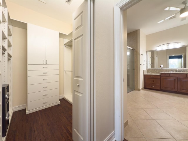 spacious closet with a ceiling fan, light tile patterned flooring, and a sink