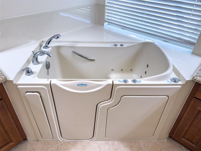 full bathroom featuring a whirlpool tub, tile patterned flooring, and vanity