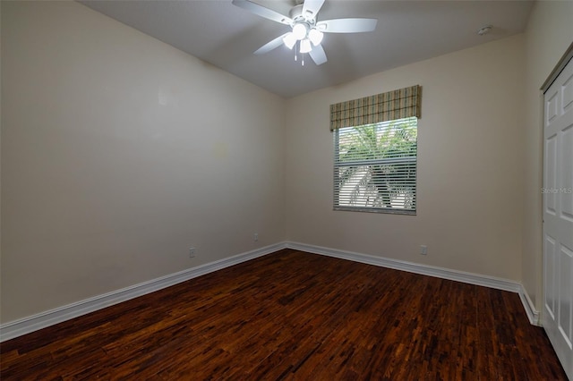 empty room featuring ceiling fan, baseboards, and dark wood finished floors