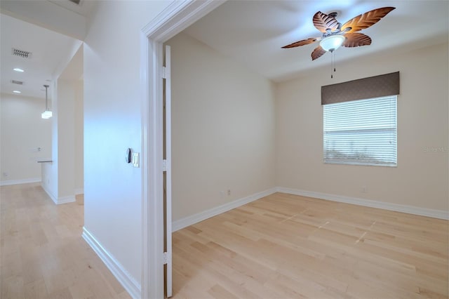 empty room featuring a ceiling fan, light wood-type flooring, visible vents, and baseboards