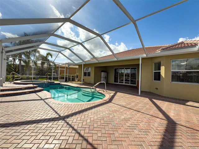 view of pool with glass enclosure, a pool with connected hot tub, and a patio