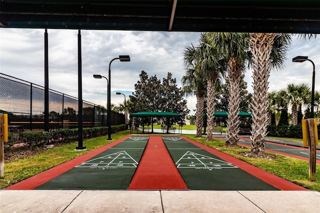 view of community with shuffleboard and fence