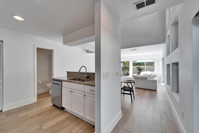 kitchen with sink, light hardwood / wood-style flooring, white cabinets, and dishwasher