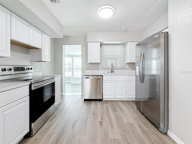 kitchen with stainless steel appliances, light hardwood / wood-style floors, sink, and white cabinets