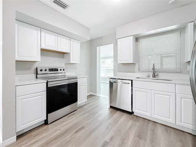 kitchen featuring sink, stainless steel appliances, light hardwood / wood-style floors, and white cabinets