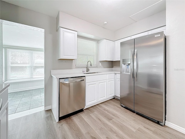 kitchen featuring light wood-type flooring, appliances with stainless steel finishes, sink, and white cabinets