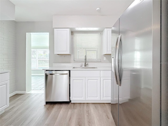 kitchen with white cabinetry, appliances with stainless steel finishes, sink, and light wood-type flooring