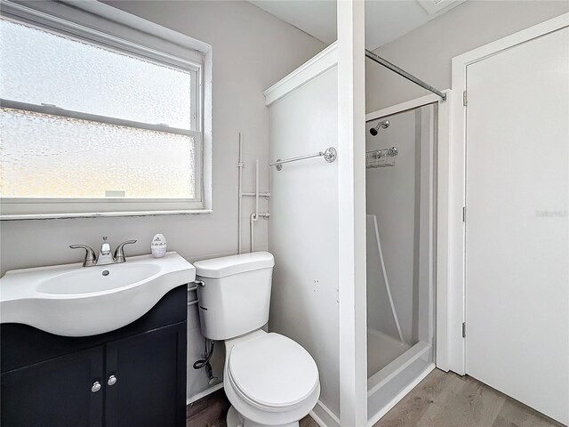 bathroom featuring vanity, toilet, hardwood / wood-style floors, and a shower