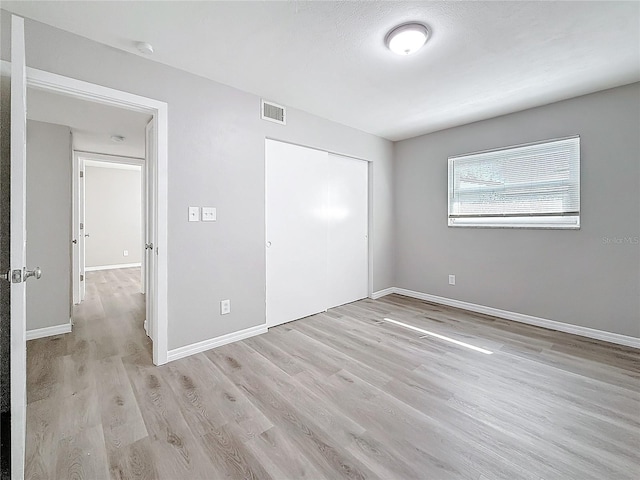 unfurnished bedroom with light hardwood / wood-style floors and a closet