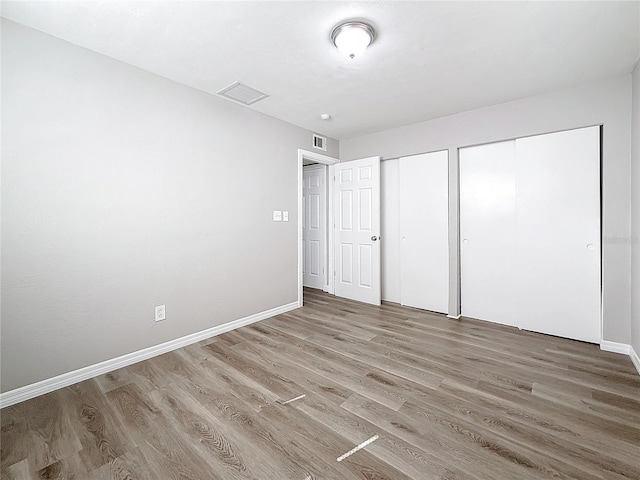 unfurnished bedroom with two closets and hardwood / wood-style flooring