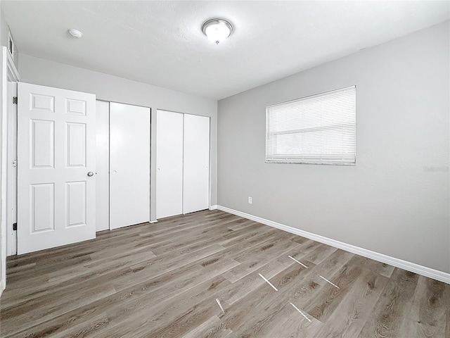 unfurnished bedroom with multiple closets and hardwood / wood-style flooring