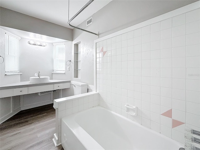 bathroom featuring tiled shower / bath, wood-type flooring, and vanity