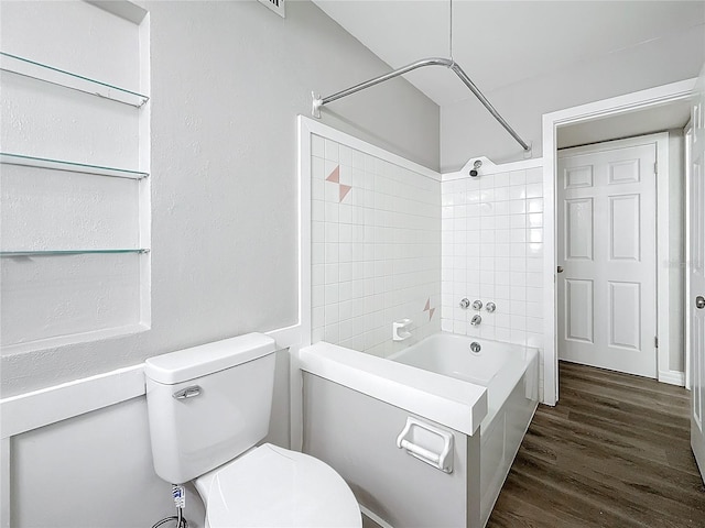 bathroom featuring hardwood / wood-style floors, tiled shower / bath combo, and toilet