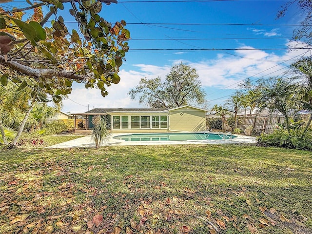 back of property featuring a patio, a fenced in pool, and a lawn