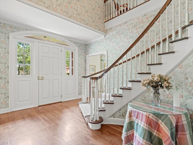 foyer entrance with hardwood / wood-style flooring and crown molding