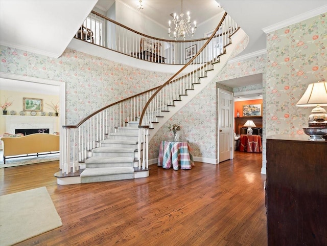 stairway featuring hardwood / wood-style floors, crown molding, a chandelier, and a high ceiling