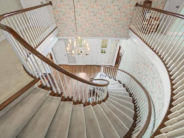 stairs featuring hardwood / wood-style floors, a towering ceiling, and a chandelier