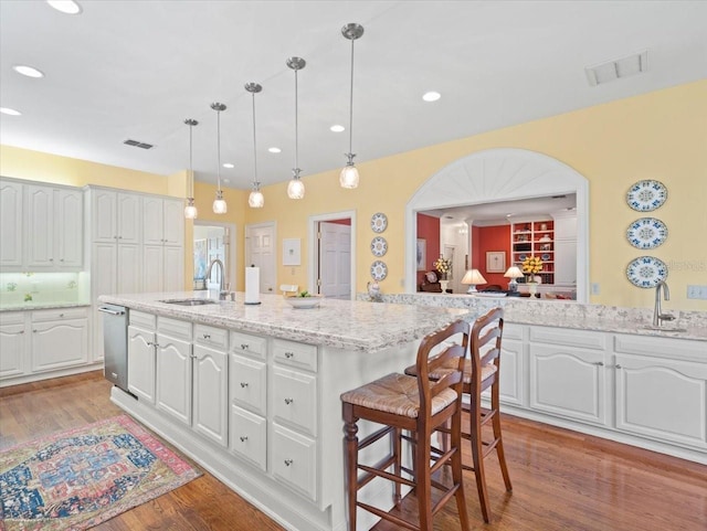 kitchen with white cabinetry, sink, decorative light fixtures, and a kitchen island with sink