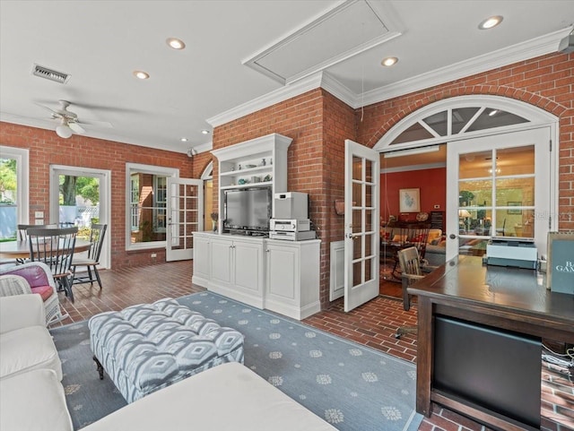 living room featuring ornamental molding, french doors, ceiling fan, and brick wall