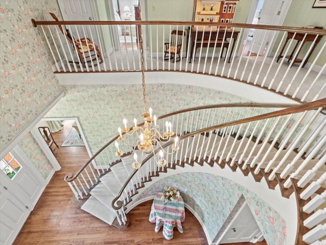 staircase with wood-type flooring and an inviting chandelier