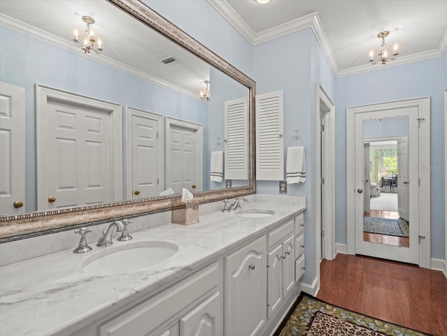 bathroom featuring vanity, crown molding, wood-type flooring, and a chandelier