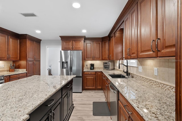 kitchen featuring stainless steel appliances, light stone countertops, sink, and light wood-type flooring