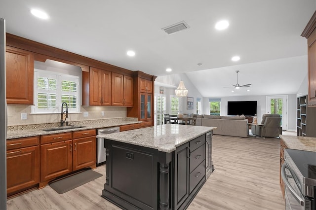 kitchen featuring sink, appliances with stainless steel finishes, plenty of natural light, light stone countertops, and a kitchen island