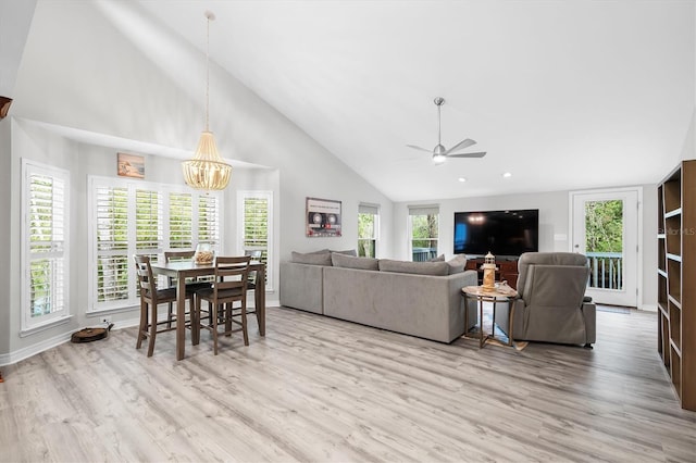 living room featuring high vaulted ceiling, ceiling fan with notable chandelier, and light hardwood / wood-style floors