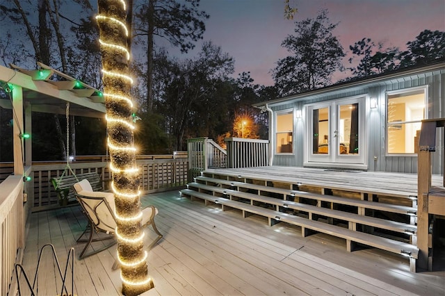 deck at dusk featuring a pergola and french doors