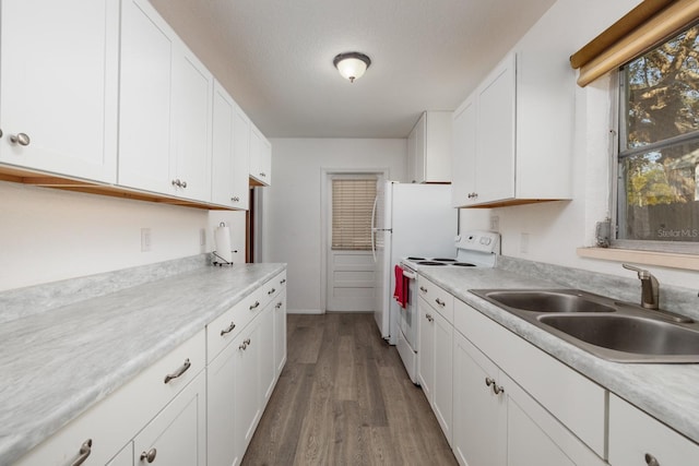 kitchen with electric stove, sink, hardwood / wood-style flooring, a textured ceiling, and white cabinets