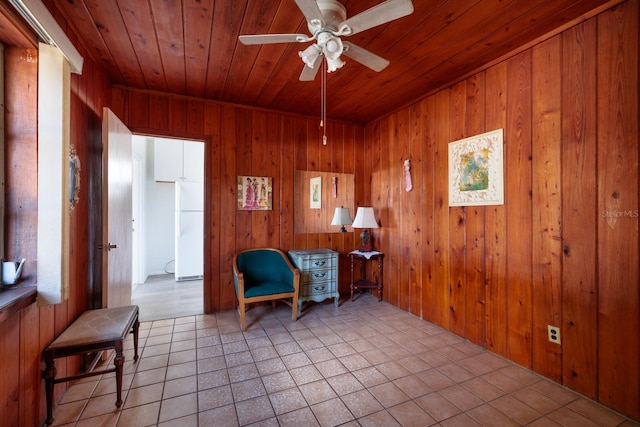 living area with ceiling fan, light tile patterned floors, wood ceiling, and wood walls