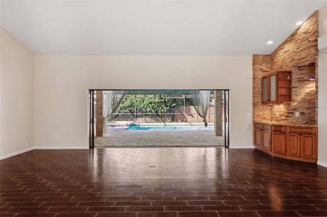 unfurnished living room featuring lofted ceiling, sink, and dark hardwood / wood-style flooring