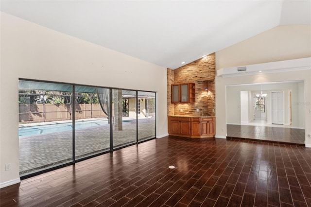 unfurnished living room featuring dark hardwood / wood-style floors, high vaulted ceiling, and a notable chandelier