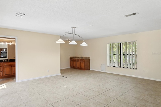 tiled spare room with sink and a textured ceiling