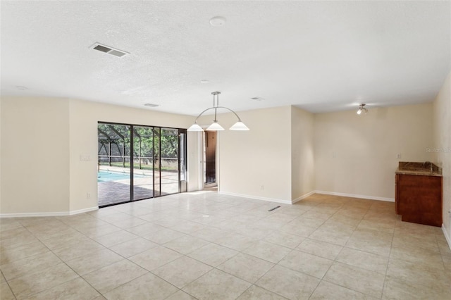 tiled empty room featuring a textured ceiling