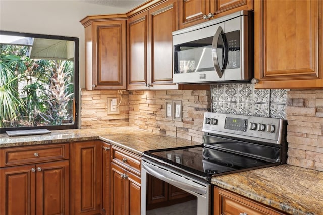 kitchen featuring backsplash, light stone countertops, and appliances with stainless steel finishes