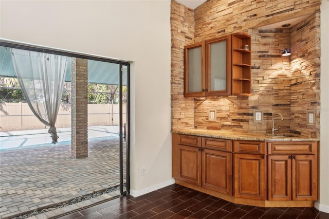 bar featuring tasteful backsplash, sink, and light stone countertops