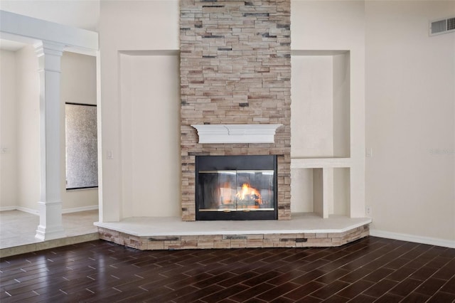 room details featuring a fireplace, wood-type flooring, and ornate columns