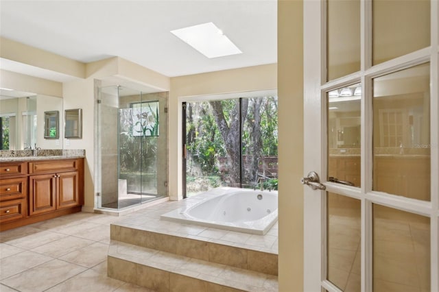 bathroom featuring vanity, tile patterned flooring, a skylight, and separate shower and tub