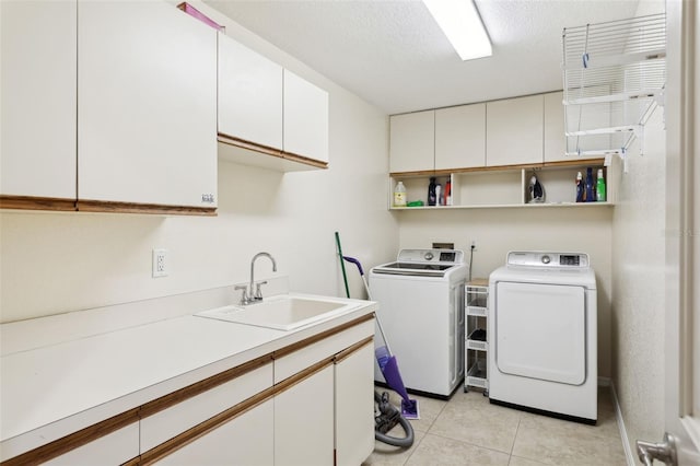 washroom featuring light tile patterned flooring, sink, cabinets, independent washer and dryer, and a textured ceiling