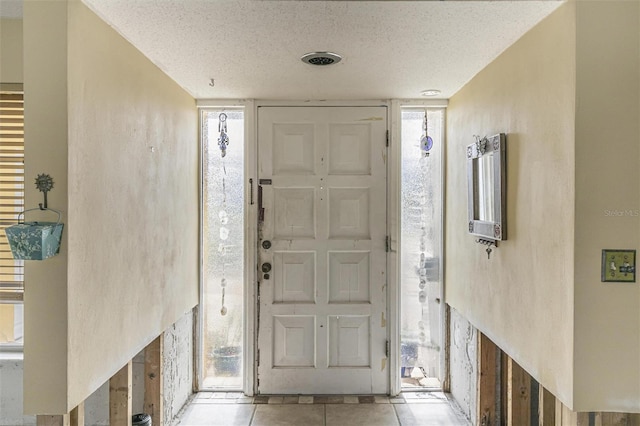 tiled entryway with a textured ceiling