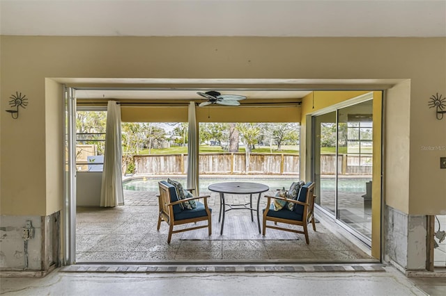 sunroom featuring ceiling fan and a water view