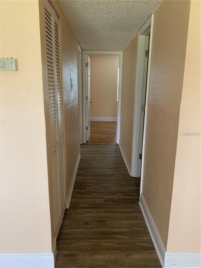 hallway featuring dark wood-type flooring and a textured ceiling